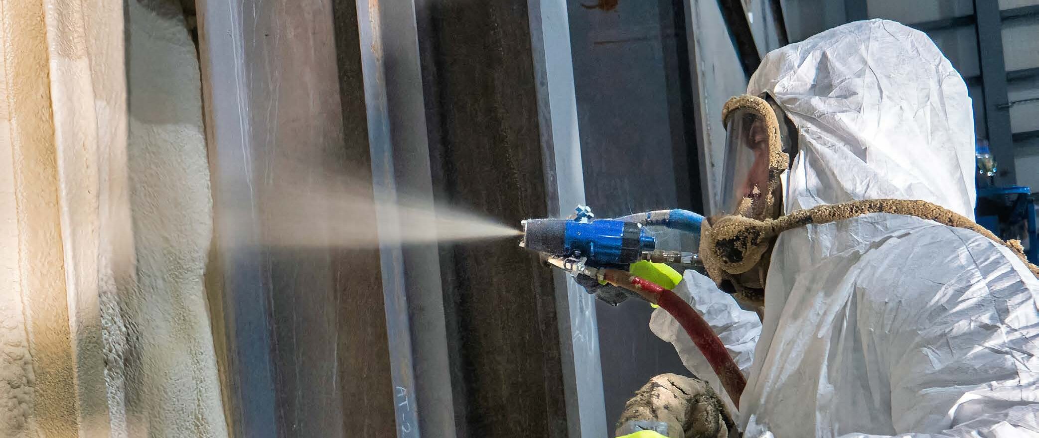 A contractor uses a Graco Fusion FX gun to spray foam insulation within the walls of a building.